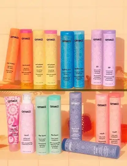 Row of colorful Amika hair care products against a coral background.